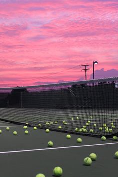 tennis balls are scattered on the court as the sun sets