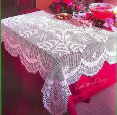 the table is covered with white lace and pink flowers