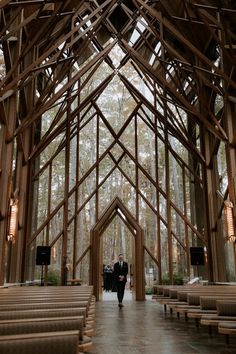 the inside of a wooden church with pews and lights hanging from it's ceiling