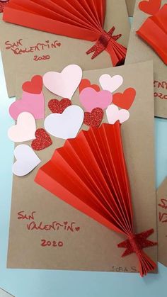 four valentine's day cards with red and pink paper hearts on brown envelopes