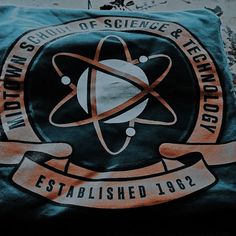 a green t - shirt with an emblem on it that says, world school of science & technology established 1932