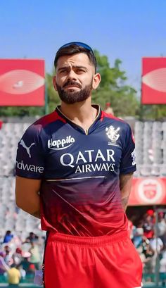 a man with a goatee standing in front of a crowd wearing red and blue soccer uniforms