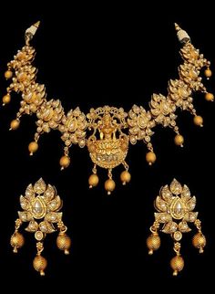 Traditional Indian temple bridal jewelry with stunning pearl stone-setting on a gold plated necklace & earrings. This temple choker jewelry set is elaborated with a goddess motif design pendant, making it one of a kind. Gold plated choker necklace with goddess engraved & floral design adorn this bridal neckpiece.  Stunning golden ball drops on this jewelry set is sure to make you feel like a million bucks with their elaborating handcrafted design. This short necklace set comes along with a beaut Gold Jewelry With Peacock Design For Navratri, Gold Jewelry Sets With Peacock Design For Festivals, Gold Peacock Design Jewelry Sets For Weddings, Gold Bridal Necklace With Peacock Design For Celebration, Spiritual Wedding Jewelry With Peacock Design, Gold Jewelry With Stone Work For Navratri, Gold Temple Necklace With Stone Work For Diwali, Gold Kundan Jewelry Set With Peacock Design, Gold Plated Temple Jewelry Sets