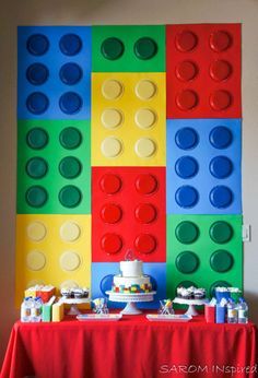 a table topped with cake and legos next to a wall made out of blocks