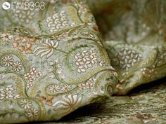 an image of a close up view of a green and gold paisley print fabric on a bed