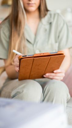 a woman sitting on a couch holding an ipad