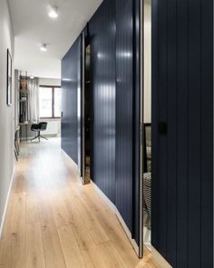 an empty hallway with dark blue walls and wooden flooring is seen in this image