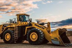 a large yellow bulldozer parked on top of a dirt field