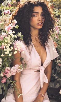 a woman sitting on a bench with flowers in front of her and holding a lit candle