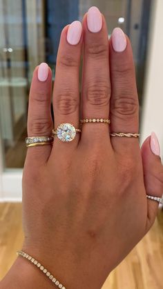 a woman's hand with three different rings on her fingers and one is holding the other