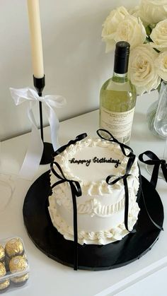 a white cake sitting on top of a table next to a bottle of wine and some chocolates