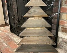 a wooden christmas tree sitting on top of a metal stand in front of a fireplace