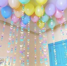 balloons and streamers hanging from the ceiling in a room with a blue door behind them