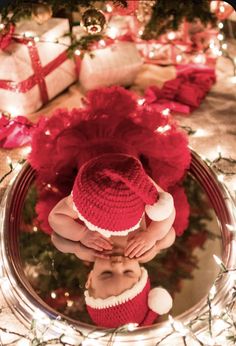 a baby wearing a red hat and diaper is looking at its reflection in a mirror