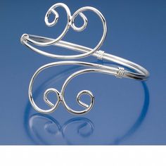 a silver cuff with two spirals on it's end and one looped in the middle