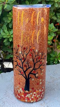 a red and gold glitter tumbler with a tree painted on it