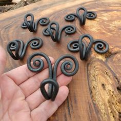 a hand is holding several small black swirl magnets