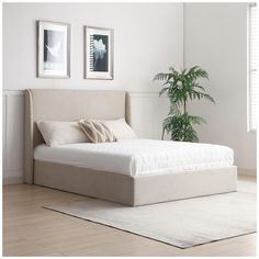 a white bed sitting on top of a wooden floor next to a potted plant