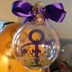 a glass ornament with an anchor on it and a purple ribbon tied around the top