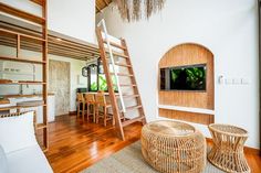 a living room filled with furniture and a flat screen tv mounted on a wall above a wooden ladder