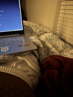 an open laptop computer sitting on top of a bed