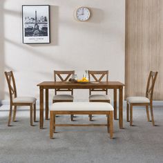 a dining table with four chairs and a clock on the wall