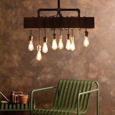 a green chair sitting under a chandelier filled with light bulbs