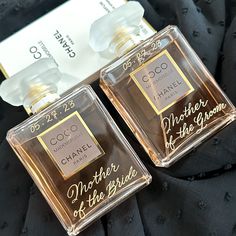 two bottles of perfume sitting next to each other on a black cloth covered tablecloth