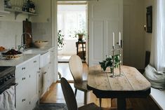 a wooden table sitting in front of a refrigerator freezer next to a vase with flowers on it