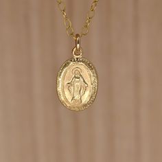 "Gold Virgin Mary Pendant Necklace. Miraculous Medal Necklace. A Miraculous Medal necklace in all 14K gold filled materials. The tiny pendant is understated and lightweight, yet sturdy. It measures approximately 12X9mm  (about 1/2 inch X 5/16 inch). It shows an image of the Virgin Mary crowned with a halo. The tiny letters around the circumference of the pendant read: \"O Mary conceived without sin pray for us who have recourse to Thee. \" What is gold-filled? Gold-filled jewelry contains almost 100 times more gold than gold-plated jewelry. Get the look and quality of karat gold at a fraction of the price.Find similar items in my shop: Browse my shop: ALLDANAE.etsy.com" Miraculous Medal Necklace, Saint Necklace, Tiny Pendant, Christian Necklace, Saints Medals, Miraculous Medal, Small Pendant, Virgin Mary, Gold Filled Jewelry