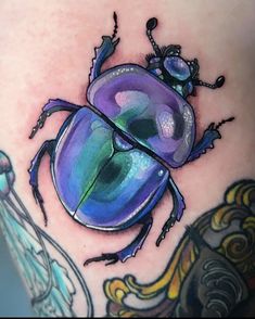 an image of a colorful beetle tattoo on someone's leg with the caption instagram