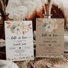 two wedding stationery cards with flowers on them sitting on a table next to a basket