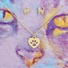 a cat's paw and heart shaped necklace with matching earring set on a purple background