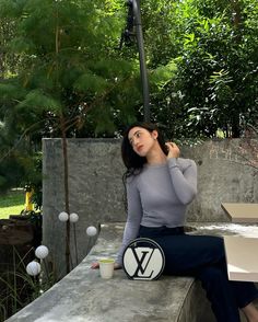 a woman sitting on top of a cement bench next to a box and lamp post