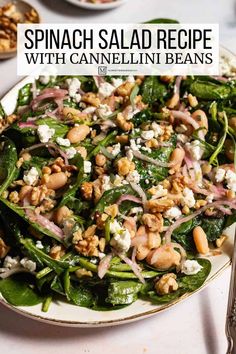 spinach salad with cannellini beans and feta cheese on a white plate