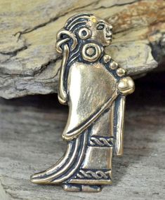 a gold and silver broochle with an image of a woman holding a bird