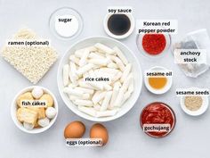 ingredients to make an egg cake laid out in bowls on a white surface with labels