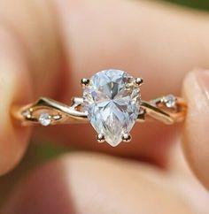 a woman's hand holding an engagement ring with a light blue diamond in it