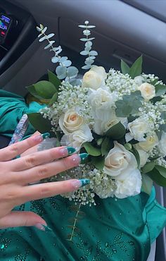 a woman in a car with flowers and nails on her hand next to a bouquet of white roses