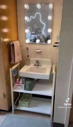 a bathroom with a sink, mirror and lights on the wall above it's door