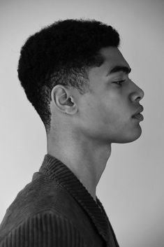 a black and white photo of a young man with an afro hairstyle looking off to the side