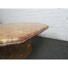 an old table sitting in front of a white brick wall with no one on it