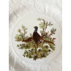 a plate with a bird painted on it sitting on a tablecloth covered table cloth