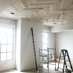 an empty room with ladders and windows in the corner, all being painted white