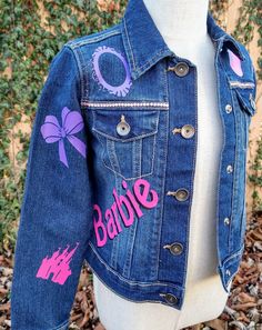 This unique Barbie themed denim jacket adds flair to any wardrobe. Its lightweight denim fabric is perfect for all-day wear, while the pink, purple and black colors bring a one-of-a-kind look. Get dolled up in this custom denim jacket, and make a bold statement! These jackets run TRUE TO SIZE. Please note that jackets are personalized and made to order. They will not always be exact replicas. Denim color may vary. Barbie Silhouette, Lightweight Denim Jacket, Custom Denim Jacket, Custom Denim, Denim Color, Colored Denim, Denim Fabric, Purple And Black, Short Sets