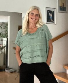 a woman standing in a living room next to a stair case with pictures on the wall