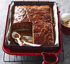 a loaf of cake sitting on top of a pan next to ice cream and spoons