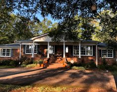 a brick house with white trim and large trees