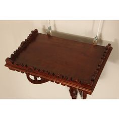 a wooden tray with metal handles on a white wall behind it is hanging from the ceiling