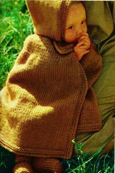 a child wrapped in a blanket sitting on the grass